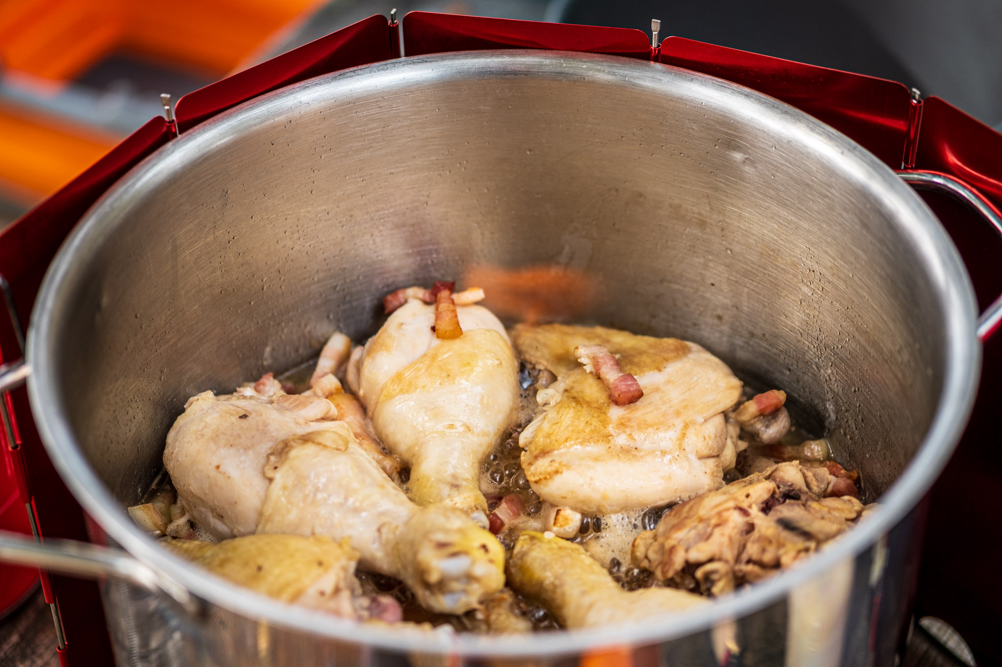 Chicken drumsticks and thighs in a pot frying in bacon for coq au vin