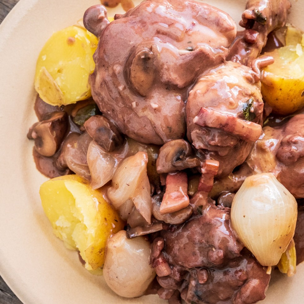 Plate of coq au vin served with potatoes, mushrooms and onions