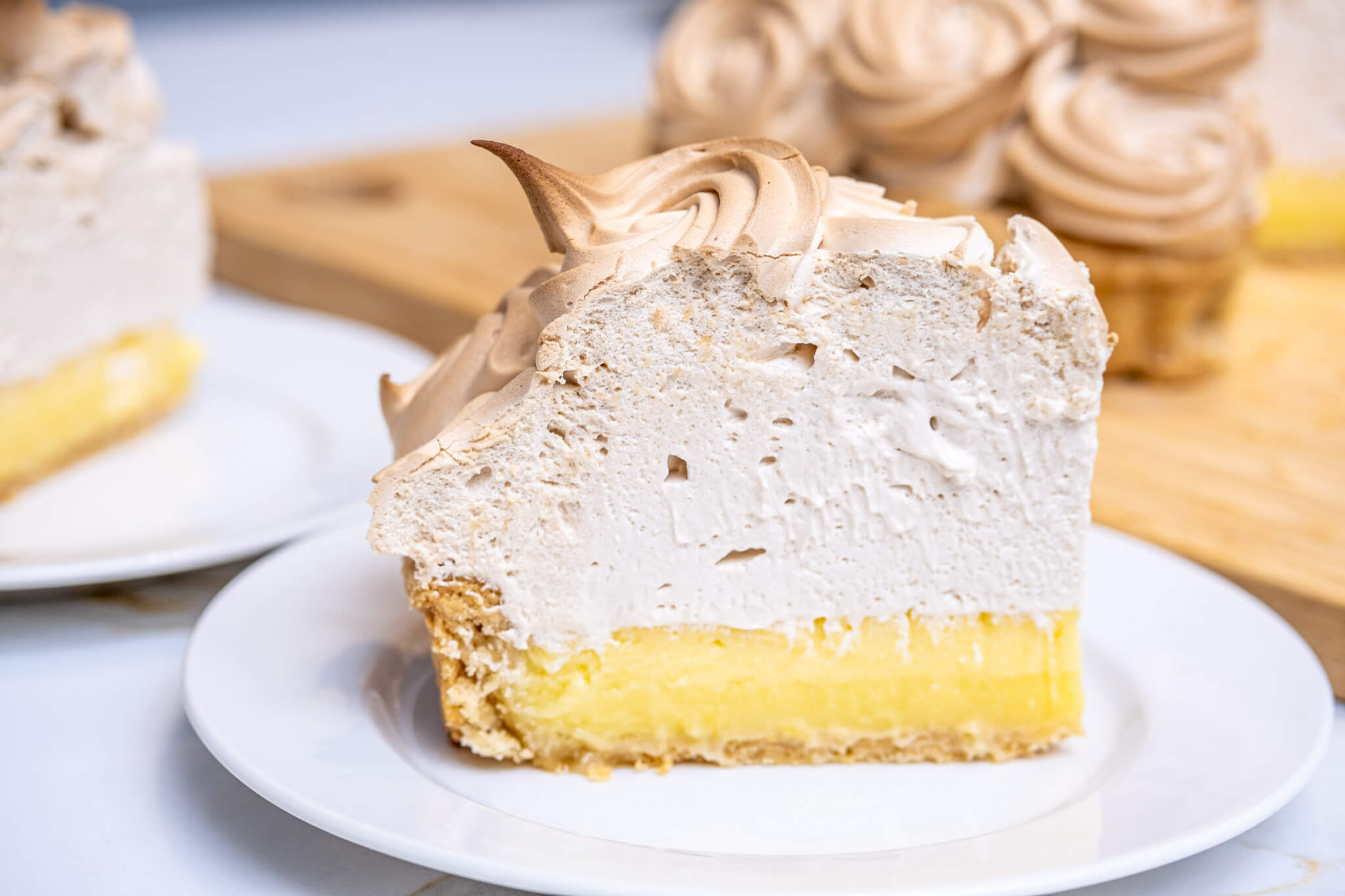 Slice of lemon-lime meringue tart with a generous amount of Italian meringue