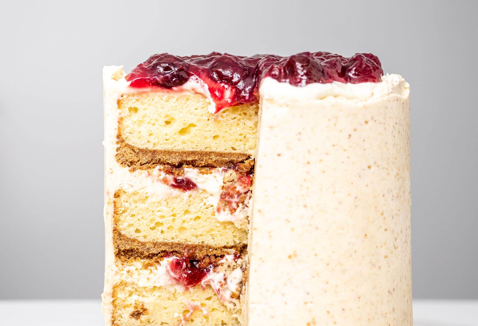 4 layer cake inspired by cherry cheesecake with graham crumb crust on each layer, cream cheese filling and sour cherry sauce