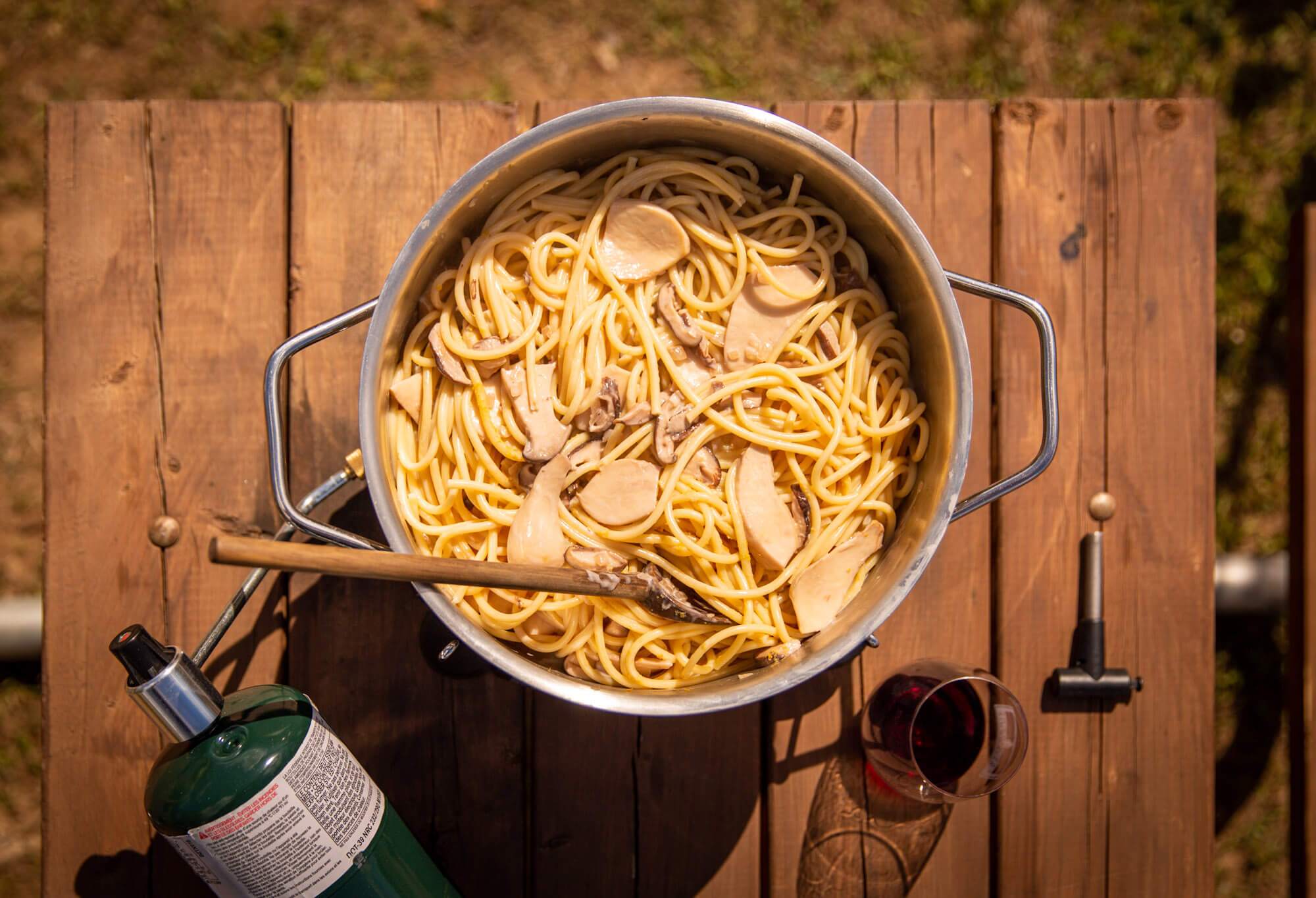 Vegan mushroom cream sauce pasta on a camp stove on a picnic table
