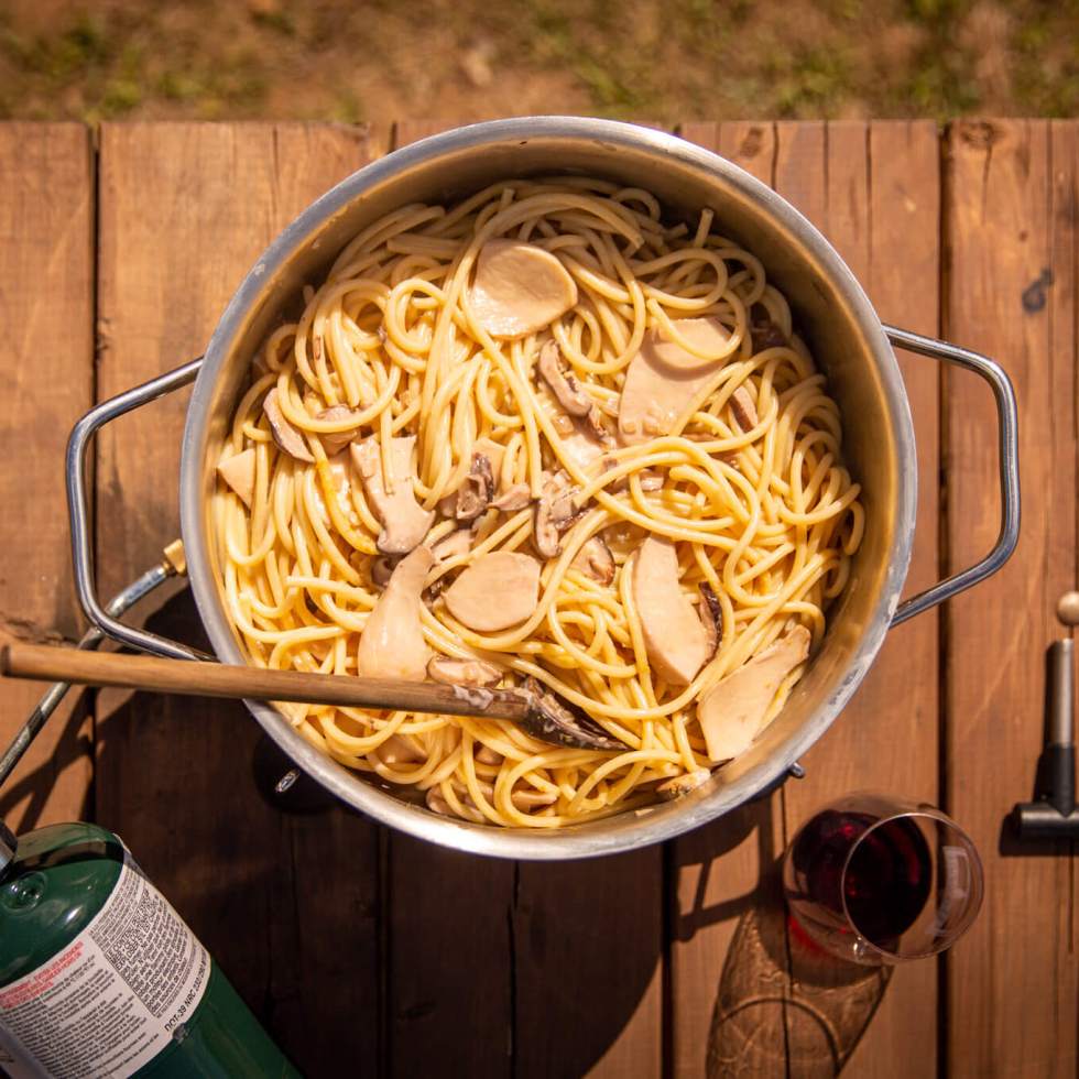 Vegan mushroom cream sauce pasta on a camp stove on a picnic table