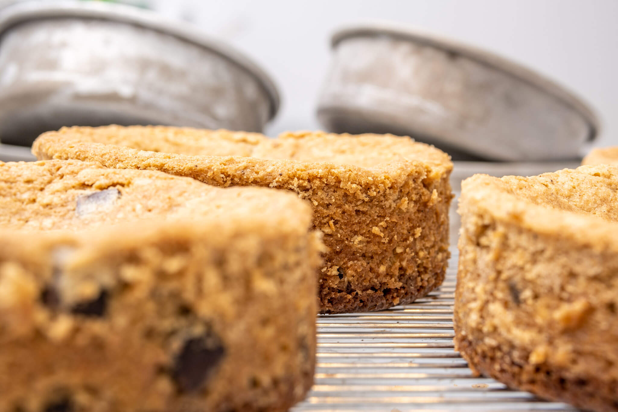 Cake layers cooling on a rack with cake pans in the background