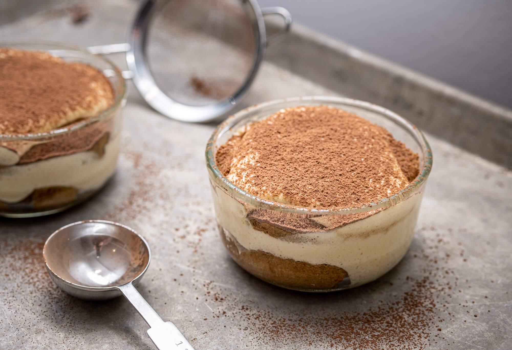 Tiramisú in a glass ramekin dusted with cocoa powder