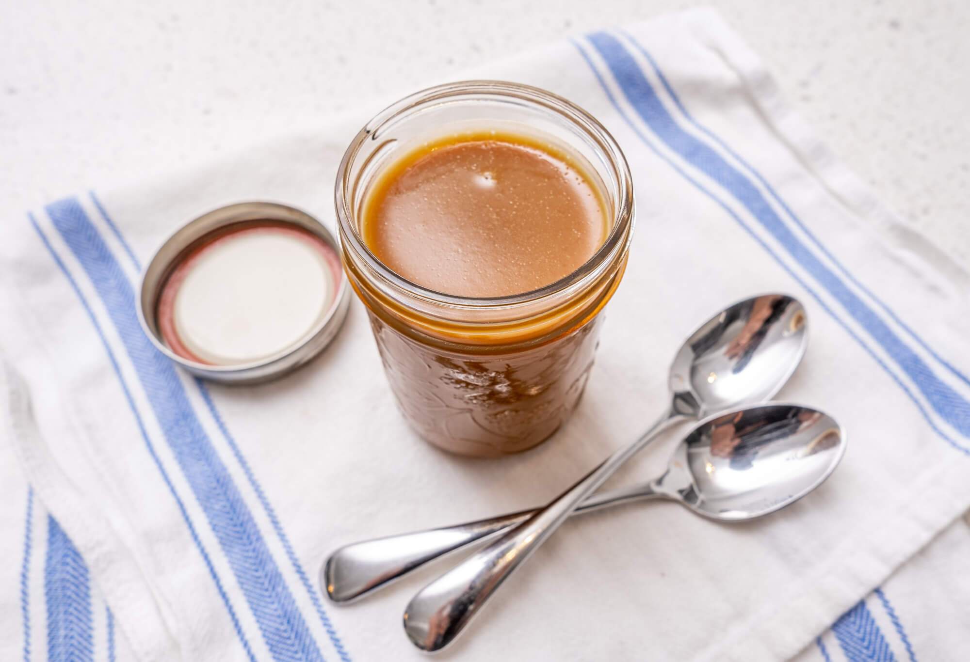 A mason jar of vegan salted caramel sauce on a cloth dish towel
